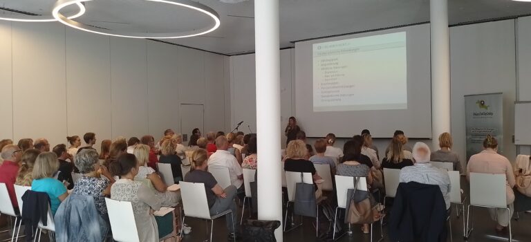 Fachtag zum Thema Psychische Gesundheit in der Arbeitswelt Sitzendes Publikum in einem Veranstaltungsraum während einer Präsentation